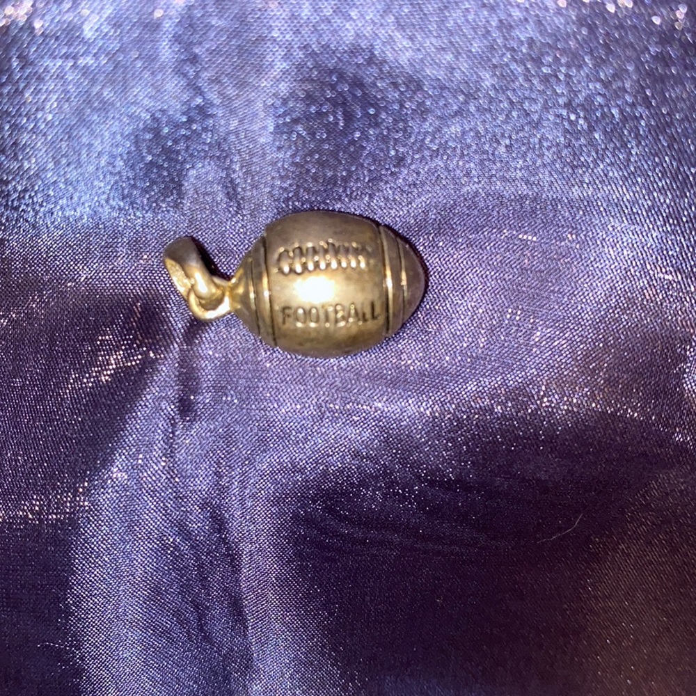 An approx. 1” heavy silvery tone football shaped pendant.